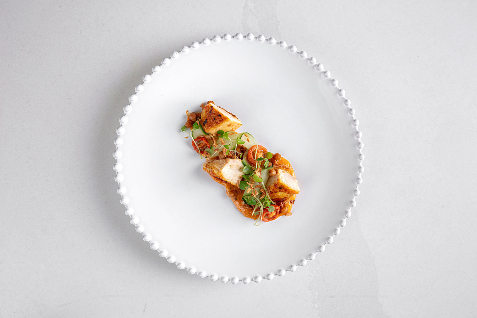a beautifully plated dish of chicken on a white plate and marble surface