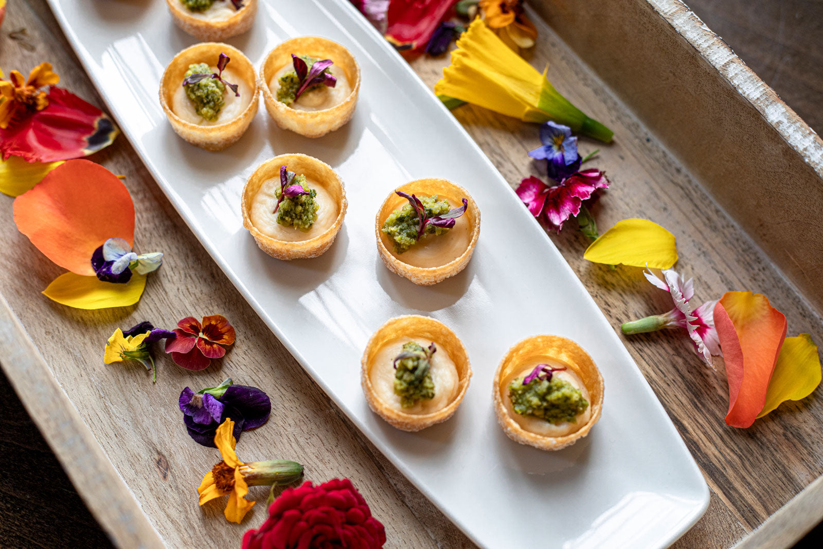 colourful seasonal canapes using fresh flowers on a wooden serving tray