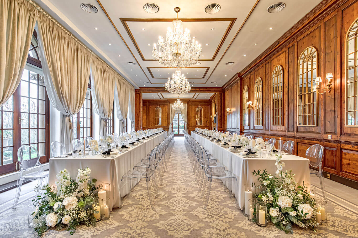 a wood panelled room in a stately home set for a wedding dinner with long tables adorned with flowers