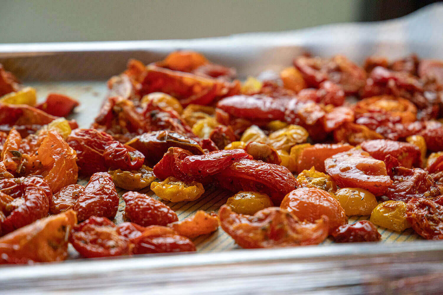 Roasted tomatoes on a baking sheet with a blurred background