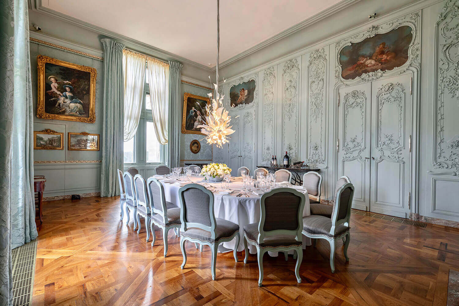 Elegant dining room with ornate walls, chandelier, and table set for dinner at Waddesdon Manor.